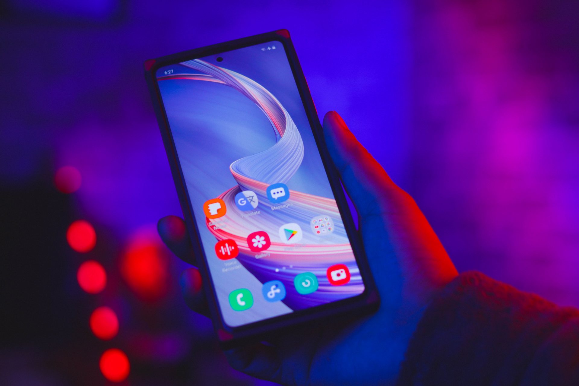 hand holding a phone with app icons on screen