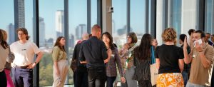 Scholars conversing in front of windows.