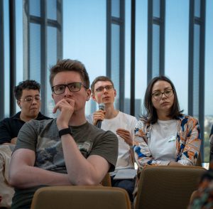 An audience with one member holding a microphone, asking a question.