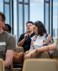 An audience with one member holding a microphone, asking a question.