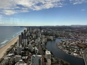 A coastal city skyline with a river flowing through it featuring a mountain range in the horizon.