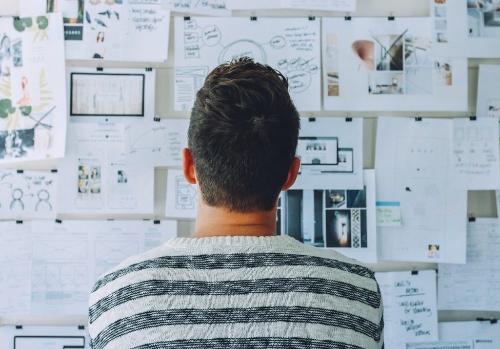 Man observing a wall covered with papers